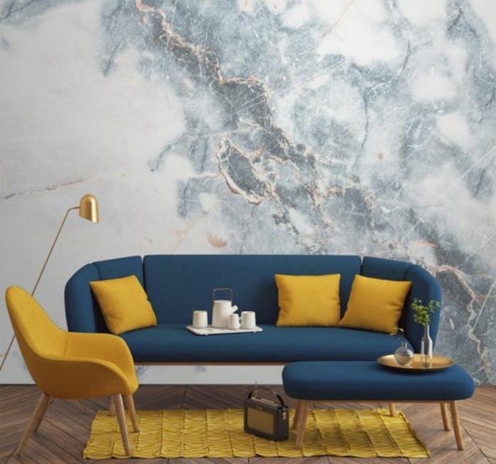 çağdaş bir oturma odasında mavi ve sarı dekorasyon, minderler, koltuk ve sarı halı, mavi tabanlı kanepe ve masa, duvar kaplaması, imitasyon mermer duvar kağıdı