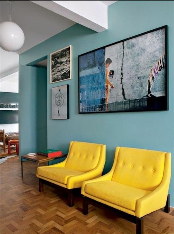 mavi ve sarı dekor fikri, pastel ton, sanatsal resimlerle süslenmiş bir duvarın arka planında sarı koltuklar, hafif parke
