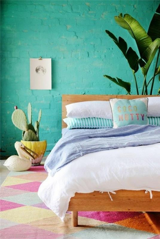 turkizna spalnica, tropske rastline, lesena postelja, večbarvna preproga, kaktus