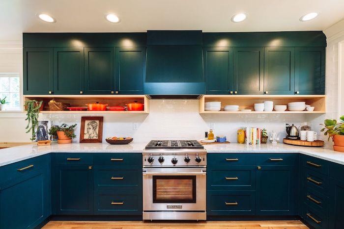beyaz mermer tezgah ve bulaşıkları saklamak için ahşap raflar ile mavi, beyaz ve turuncu bir mutfakta petrol mavisi dekor