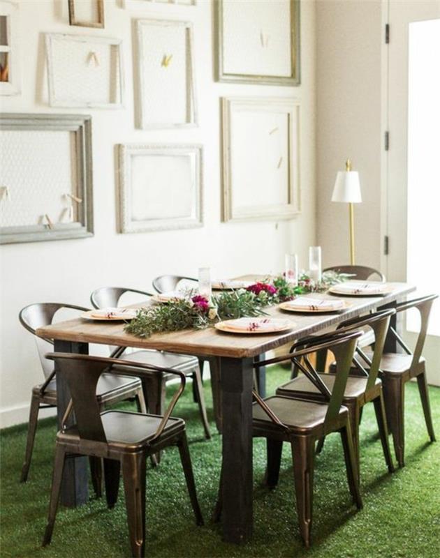 okrasite steno s praznimi belimi in sivimi okvirji, kovinskimi stoli, kmečko leseno mizo, cvetličnim središčem in krožniki, tlemi, imitacijo sveže trave