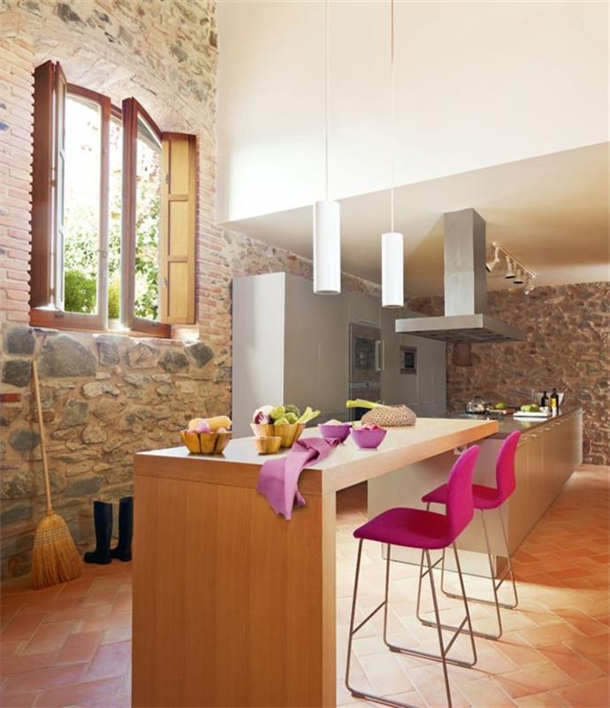 opremljena kuhinja, roza stoli, lesena kuhinja, okna, kamnita stena, bele viseče svetilke, bela stena