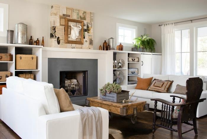 šiuolaikiškas kaimiško charakterio dekoras, baltos sofos, medinis kavos staliukas su ratukais, vintažinė apdaila, lagaminai, medinė kėdė, meniška sienų apdaila
