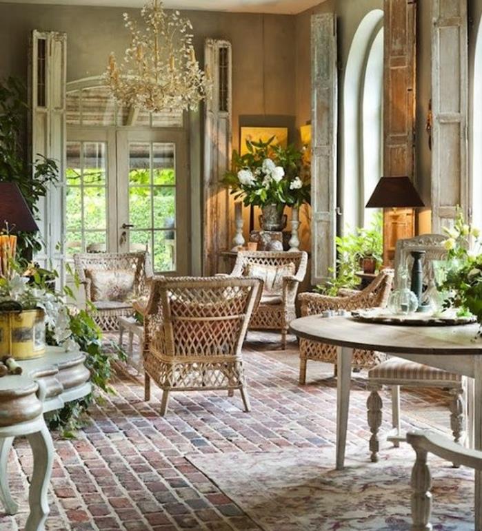 eleganten podeželski dekor, opečna tla, stoli iz ratana, siva stena, cvetlični okras, jedilnica, okrogla miza in leseni stoli, cvetlični lestenec
