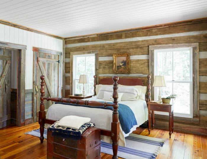podeželska elegantna spalnica, postelja iz starinskega lesa, konec postelje, starinska skrinja, stena iz lesenega nosilca, obrabljena lesena vrata, rjav paket