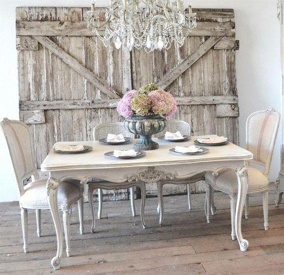 Ideja o dekorju francoske dežele, lesena miza in beli stoli, vrata iz lesenih tramov, starinski lestenec, cvetlični osrednji del