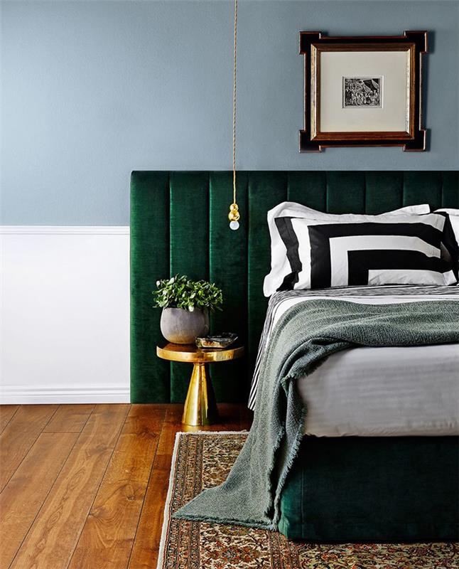dekor spalnice za odrasle z modro steno, smaragdno zeleno vzglavje, bela, črna in siva posteljnina, orientalska preproga nad rjavim parketom