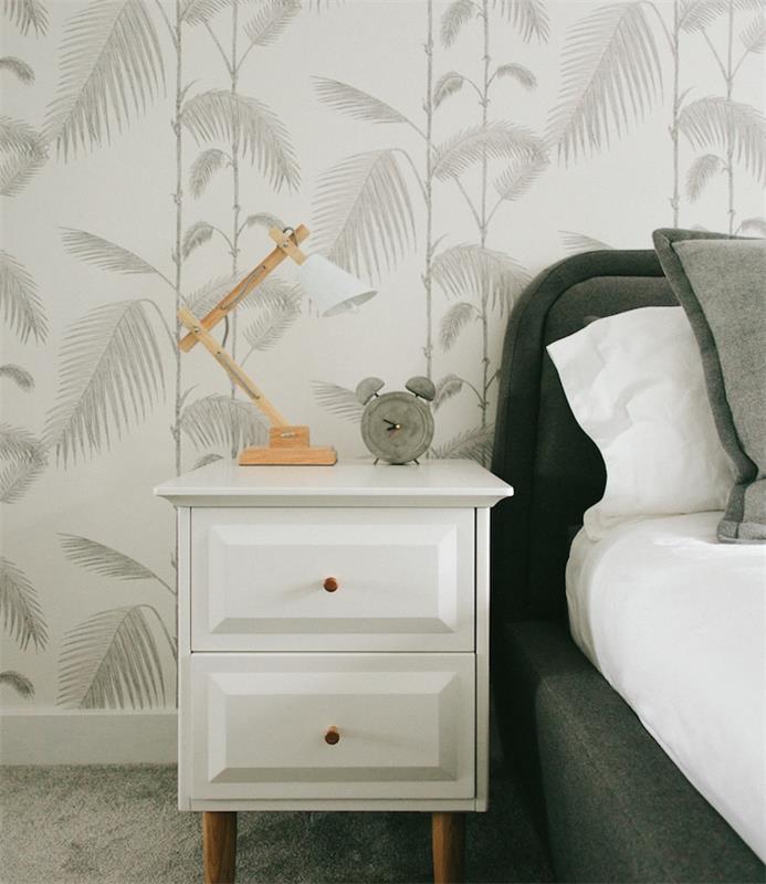 yetişkin yatak odası dekorasyonu, tropikal duvar halısı, yeşillik, beyaz arka planda grafik gri palmiye ağaçları, gri yatak ve beyaz çarşaflar, beton çalar saat, özgün tasarım lambası