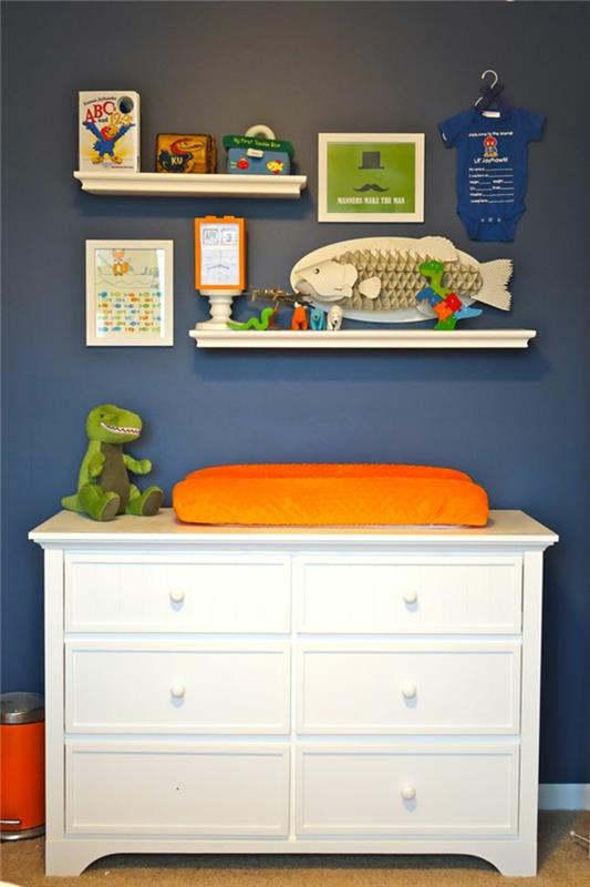 parlak renkli duvar beyaz saklama dolabı ve turuncu dekoratif elemanlara sahip beyaz raf ile ördek mavisi bebek odası