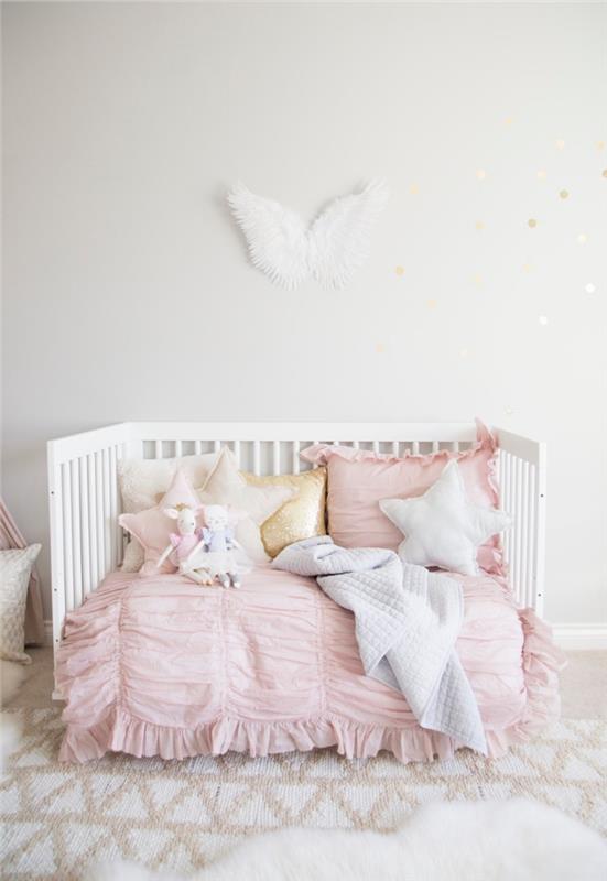 merginos kambario su kūdikio lova iš baltos medienos išdėstymas, rožinės spalvos lovos užtiesalas kartu su žvaigždžių formos pagalvėlėmis