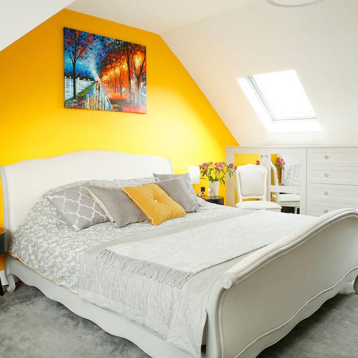 dekor za spalnico za odrasle, rumena naglasna stena, belo in sivo posteljnina, beli predalnik, puhasto siva preproga, rožnati cvetlični šopek, jesensko slikanje pokrajine