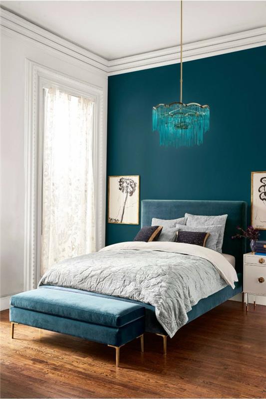 suaugusiųjų miegamasis dažomas mėlyna spalva, mėlyna lubų lempa virš lovos, mėlyna ir pilka lova, aksominis lovos suoliukas, balti naktiniai staleliai