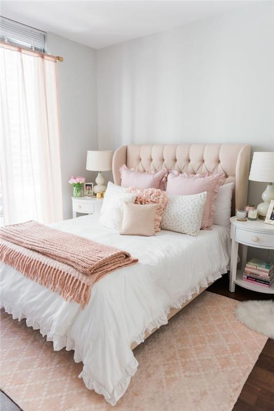 modernus suaugusiųjų miegamojo paveikslas, rožinis lovos užmetimas, rožinės pagalvėlės, kuoduotas galvūgalis, geometrinis rožinis kilimas