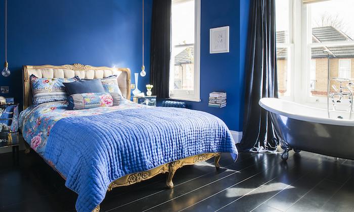 svetlo siva kad v temno modri spalnici za odrasle, baročna postelja z modrim perilom s cvetličnim potiskom, črni parket