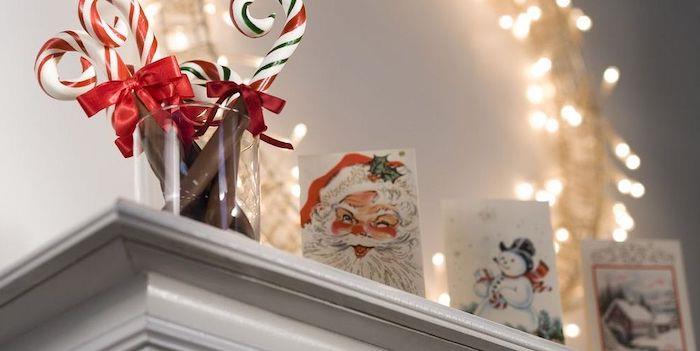 Bir ışık çelengi önünde şenlikli kartlar ve şeker çubukları ile Noel şöminesi dekorasyonu