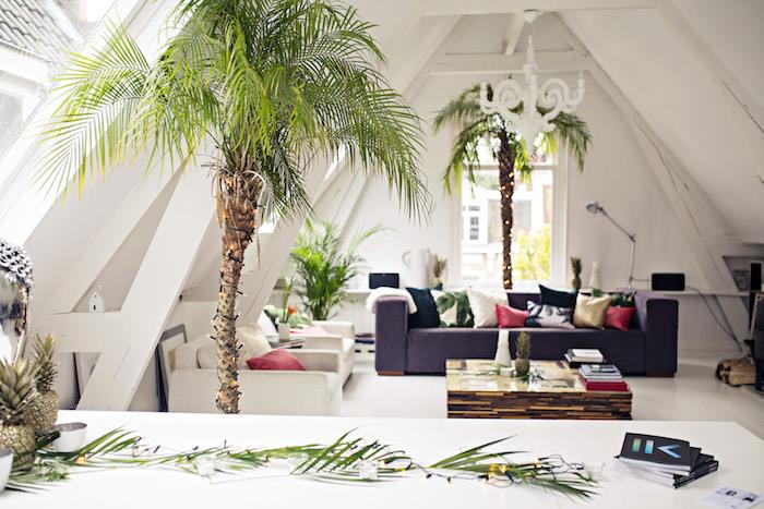 deco decocoon model, siv kavč, beli naslanjači, lesena mizica s stekleno ploščo, okrasne palme