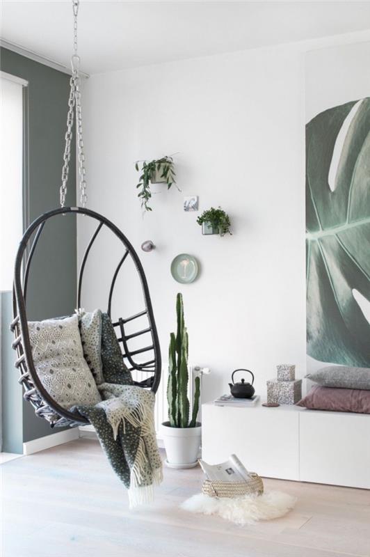 Skandinaviškas ir bohemiškas prašmatnus baltos ir žalios spalvos svetainės dekoras su nuolaidžia foteliu, pakabintu nuo lubų ir žaliais akcentais