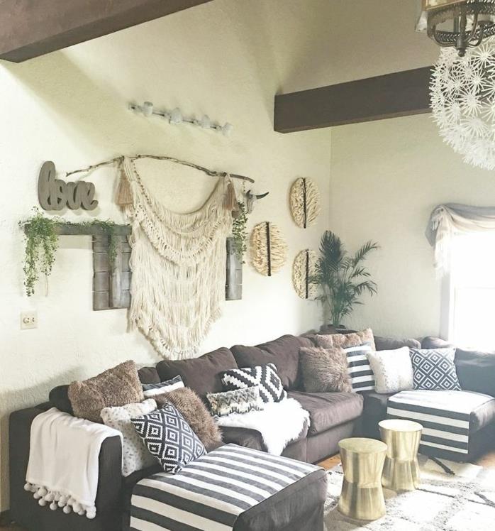 šiuolaikiškas dekoras, ruda kampinė sofa, baltos, juodos ir rudos spalvos pagalvėlės, makrame apdaila, elegantiška pakaba, būgno tipo kavos staliukas