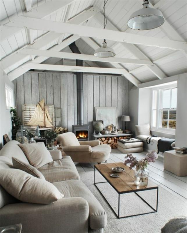 pilka sofa ir poilsio kėdė, šviesiai pilkas kilimas, medinis ir metalinis kavos staliukas. modernus židinys, skandinaviško stiliaus, pramoninės pakabos, baltas medinis stogas, kaimiška svetainė