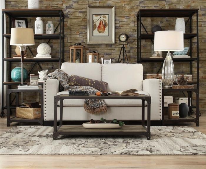 akmens siena, metalinės ir medinės lentynos, pramoninis stilius, smėlio spalvos sofa, pilkas kilimas, medinis ir metalinis žurnalinis staliukas, šviesus parketas, dekoratyviniai akcentai