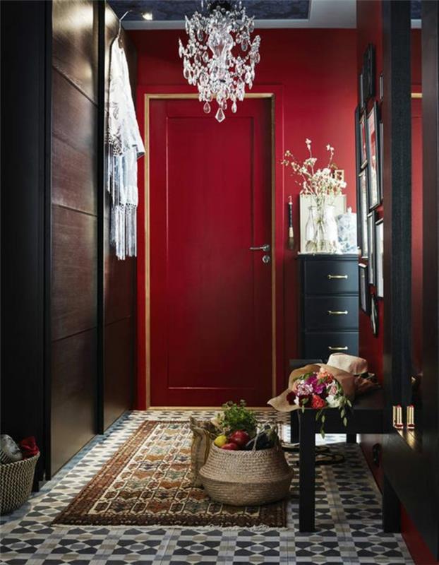 ilgas ir siauras raudonos ir juodos spalvos koridoriaus apdaila, pilkos, baltos ir smėlio spalvos plytelės, didelis kvadratinis veidrodis juodame rėmelyje, juodas suoliukas, spintelė su keturiais stalčiais, krištolo pakabinama šviesa baroko stiliaus