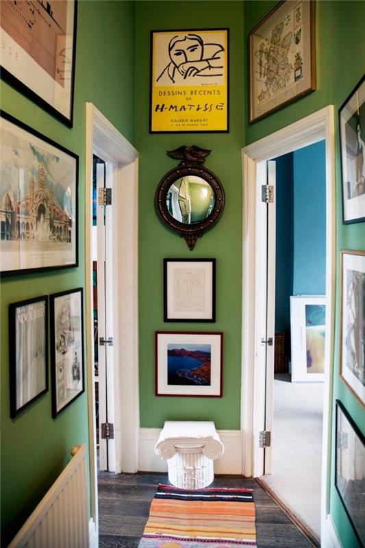 Deco ozek hodnik, pobarvan v zeleno s stenami v različnih fotookvirjih in belimi vrati