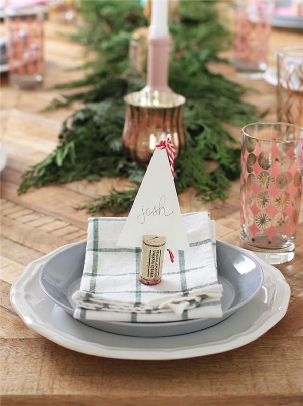Yeşil ve beyaz peçete üzerinde misafir isim etiketi, orta masa için ham ahşap masa ve yeşil dallar ile geri dönüştürülmüş mantardan Noel için orijinal yer işareti