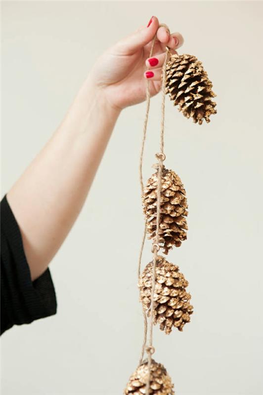 Kalėdų puošmena, kad pasidarytumėte lengvi, naudodami kankorėžius, nudažytus auksiniais dažais, sudėkite su virvele, kad padarytumėte girliandą