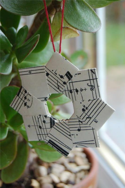 Kalėdinis „pasidaryk pats“ žvaigždė, sukurta su muzikinių partitūrų dalimis ir raudonu siūlu pakabinti ant augalo namuose ar ant Kalėdų eglutės
