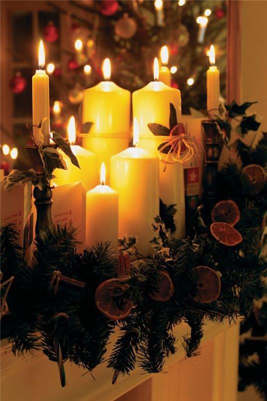 Farklı boyutlarda mumlar, yeşillikler ve kuru portakal çemberleri ile Noel dekorasyonu