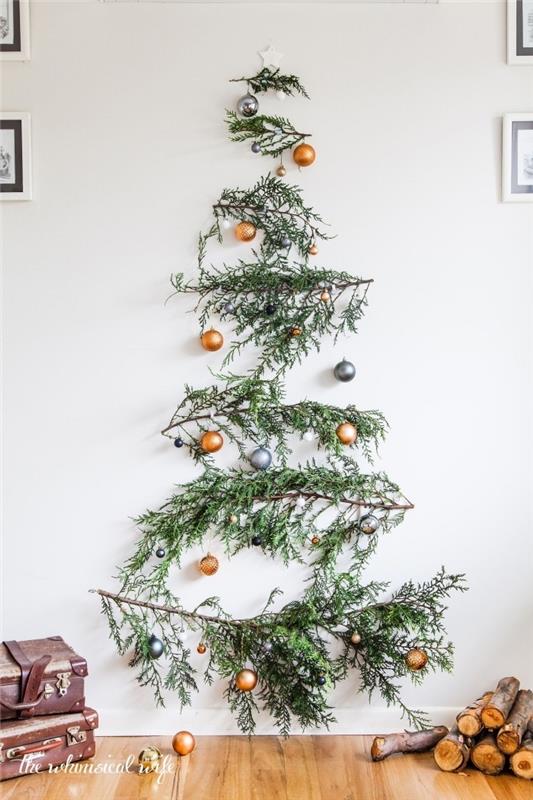 Duvarda asılı yeşil dallarla yapılmış, küçük bakır ve gümüş Noel topları ile süslenmiş orijinal doğal Noel ağacı