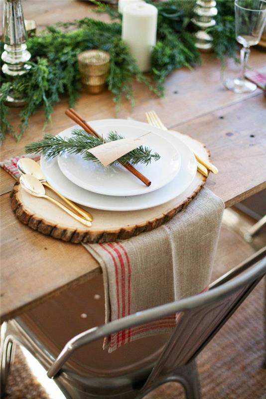 stačiakampis medinis stalas, medinis rąstas, džiuto servetėlės, baltos lėkštės, auksiniai indai, cinamono lazdelės