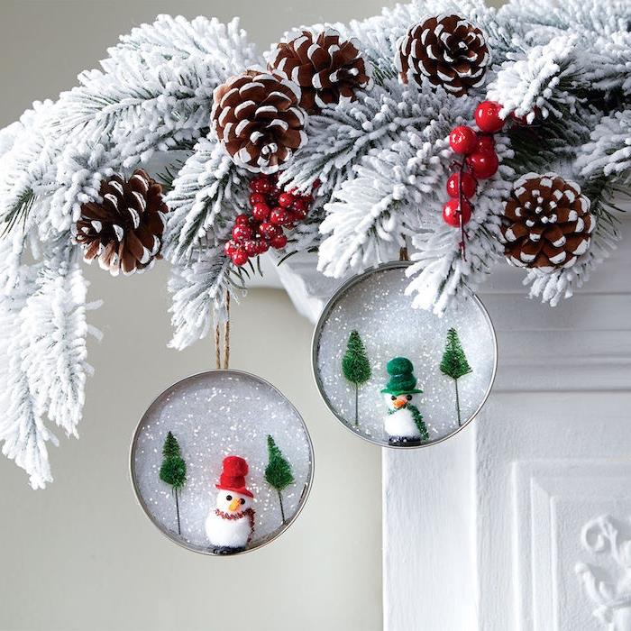 Kalėdinis židinio dekoravimas stikliniuose indeliuose su dirbtiniu sniegu ir snieguolių figūrėlėmis, kabančiomis ant balintų pušų šakų, nesudėtinga pasidaryti kalėdinę dekoraciją