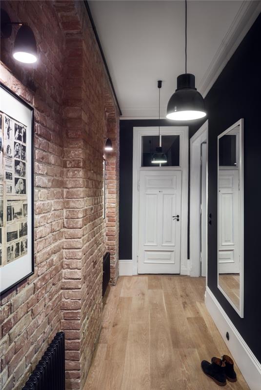 hodnik v industrijskem slogu z opečno steno, ki se popolnoma ujema s črno nasprotne stene in industrijsko razsvetljavo