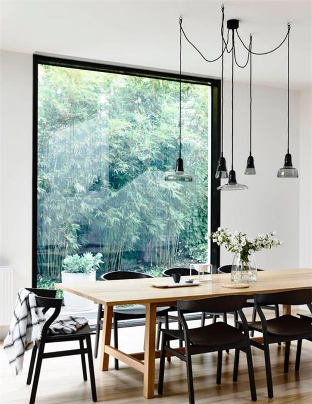 Masif ahşap masa, siyah sandalyeler, endüstriyel sarkıt lambalar, büyük pencere ile İskandinav yemek odası dekoru