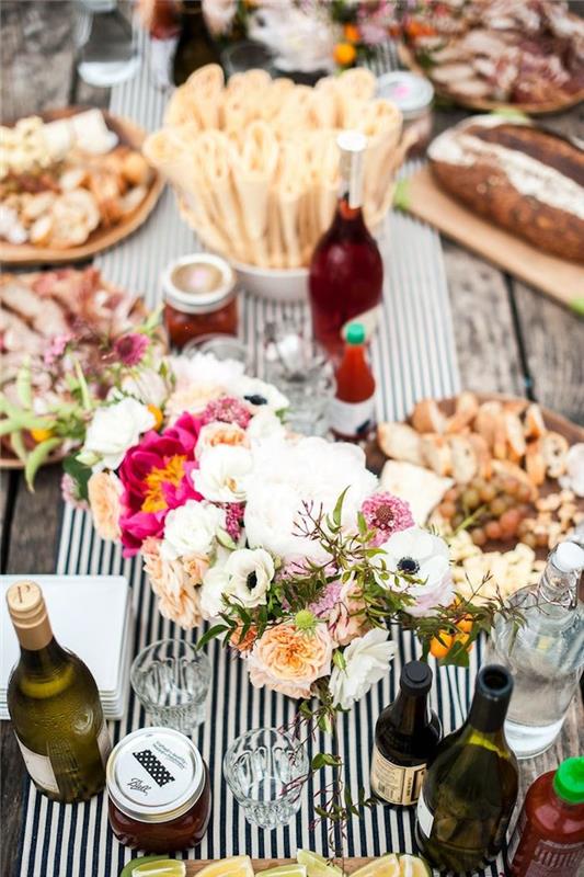 spalvinga gėlių puošmena ant juodai balto stalo bėgiko, keli patiekalai, kuriuos dalinkitės su draugais, gimtadienis lauke
