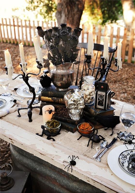 açık hava Cadılar Bayramı partisi organizasyonu, mumluklar ve gümüş kafatası ile beyaz ve siyah Cadılar Bayramı masası