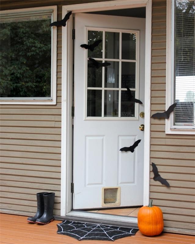 siyah kağıt yarasalar ve turuncu balkabağı içinde basit Cadılar Bayramı dekorasyonu ile beyaz ön kapı