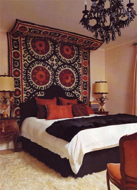 bohemiškas miegamojo dekoras, juoda liustra, minkštas kilimas, raudonos pagalvėlės, juoda galvūgalis
