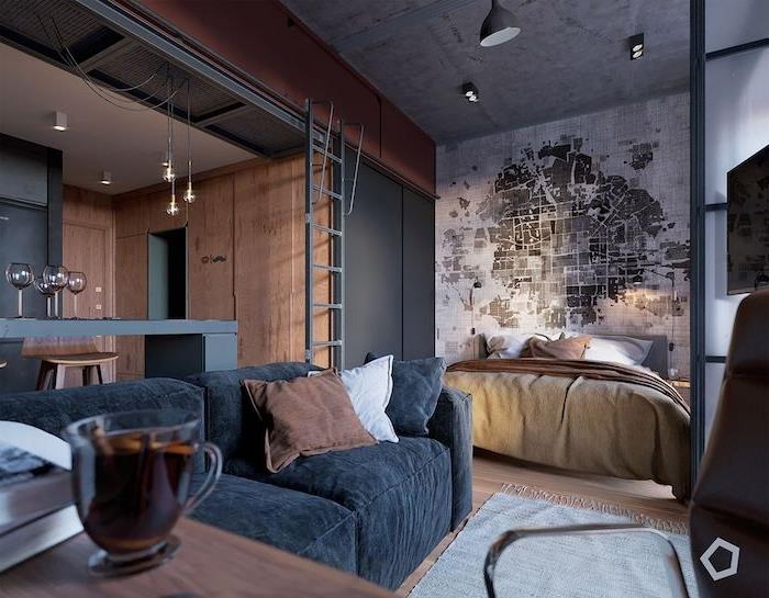 lesena in siva kuhinja, odprta za dnevno sobo s kavčem iz oglja, spalnico s posteljo in izvirnim vzglavjem ozadja, industrijsko dekoracijo podstrešja