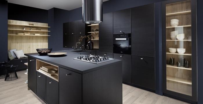 poilsio zona su šviesiai medinėmis sienomis ir pastelinių atspalvių pagalvėlėmis dekoruotas juodas suoliukas, juoda bistro virtuvė