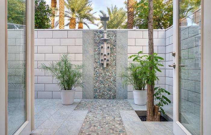 bahçede beyaz fayans duvarlı, paslanmaz çelik yağmur duşlu ve taş duvar bölmeli pinterest banyo modeli