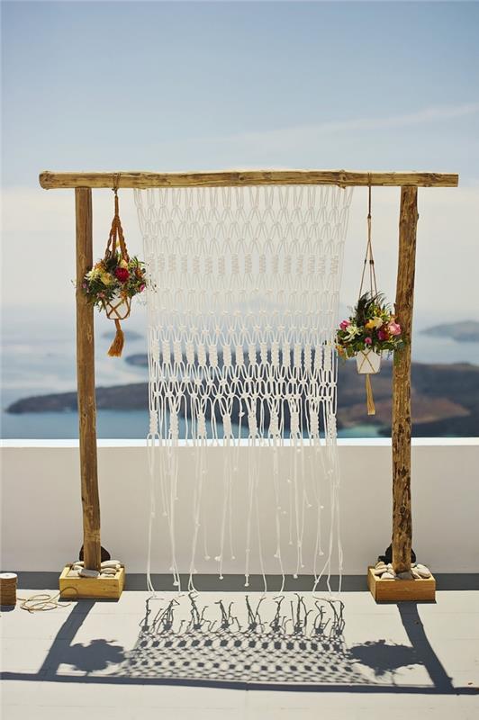 primer poročne dekoracije v slogu boho z lesenim lokom in zavesami iz makrameja, model vzmetenja rastlin v rdeči niti