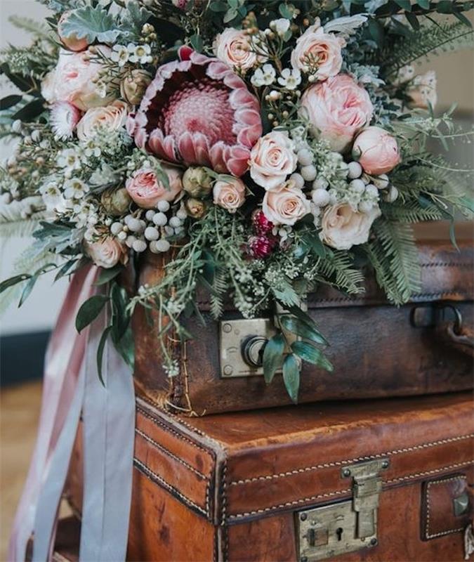 kup starodobnih usnjenih debel s šopkom rož na vrhu in rožnatim trakom, vintage poročni dekor