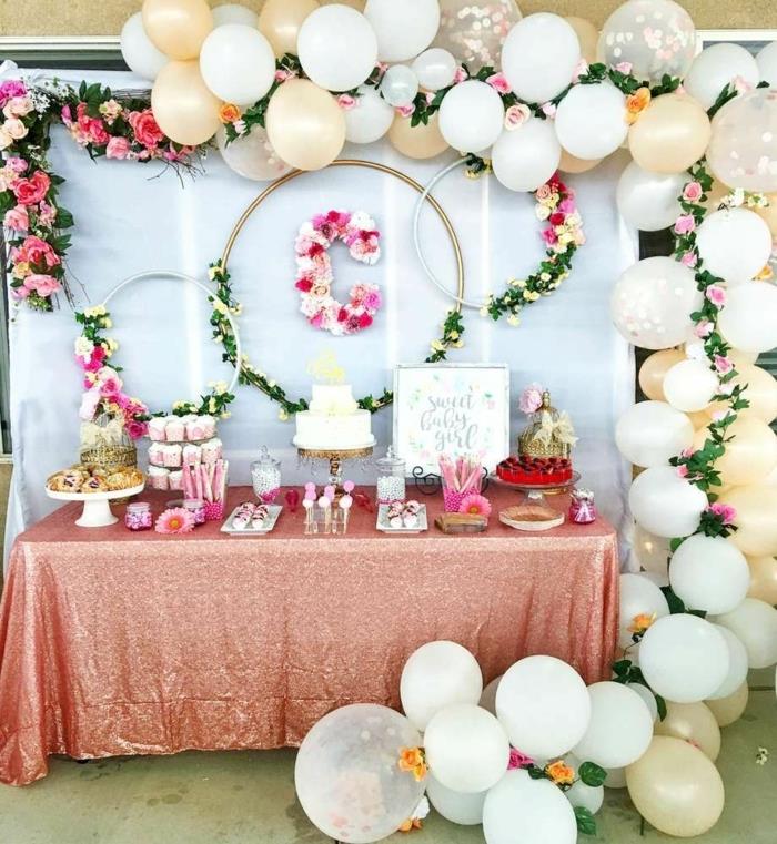 baliono arka, vestuvių arka, žiedai, papuošti žaliais lapais ir gėlėmis, peleninė rožinė staltiesė, pyragai, rožiniai bandelės