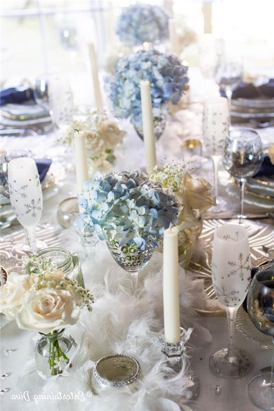 novoletna dekoracija z vrtnicami in modrimi cvetovi v kozarcih za šampanjec namizna dekoracija s perjanicami