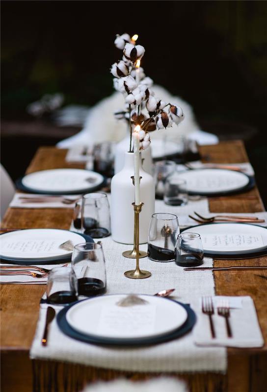 rustik bir masa bakır çatal bıçak takımı üzerinde mumlar ve pamuk dalları ile minimalist yeni yıl dekoru