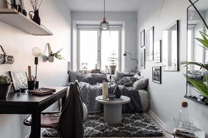 majhen dolg dekor stanovanja z belimi stenami, siv kavč, ogljeno siva preproga, siva mizica, lesena miza