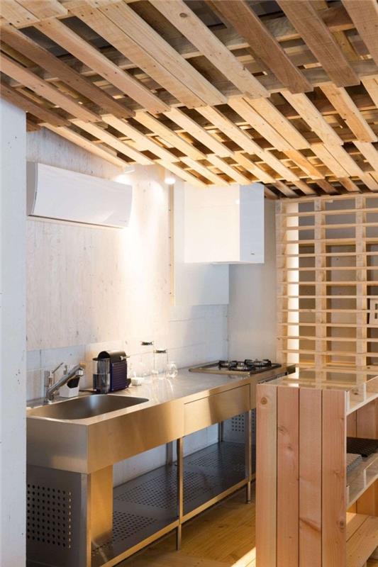 model majhne kuhinje z belimi stenami s stropom palete, ideja ločitve prostora v reciklirani paleti, na primer lesena obloga