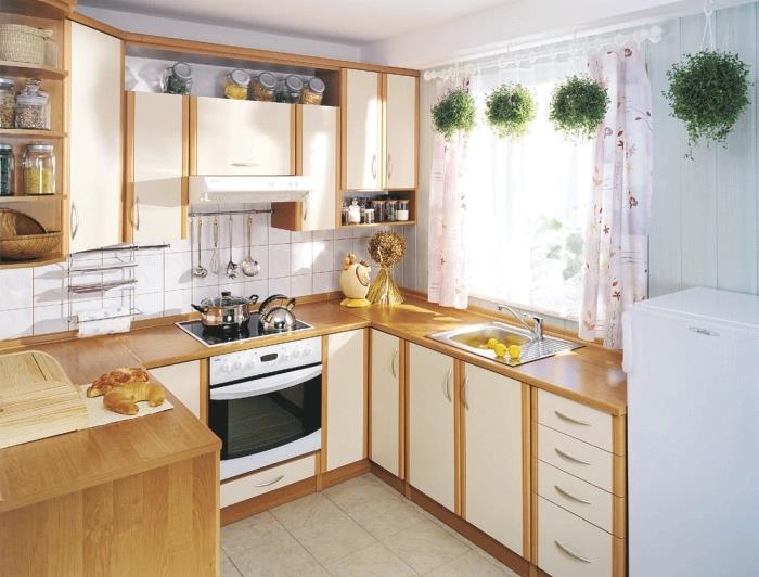 postavitev majhne kuhinje v obliki črke U s pohištvom iz belega in rjavega lesa, podeželski dekor s kratkimi zavesami v cvetličnem dizajnu
